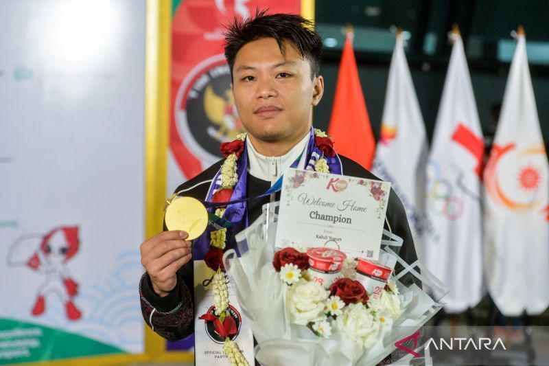 Atlet angkat besi Indonesia memegang medali dan buket bunga saat penyambutan kepulangan