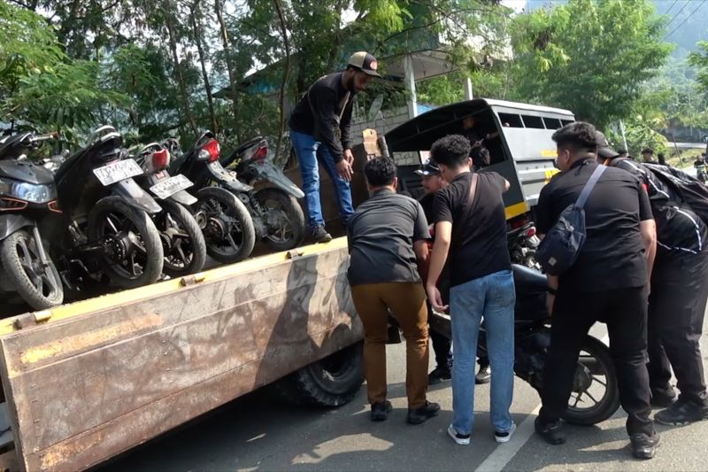 Petugas memuat deretan sepeda motor yang diamankan ke atas truk di pinggir jalan