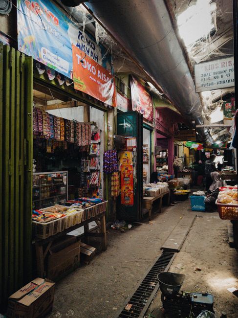 Lorong pasar tradisional yang ramai dengan deretan kios berwarna-warni dan hasil bumi segar