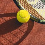 Bola tenis dan raket di atas lapangan