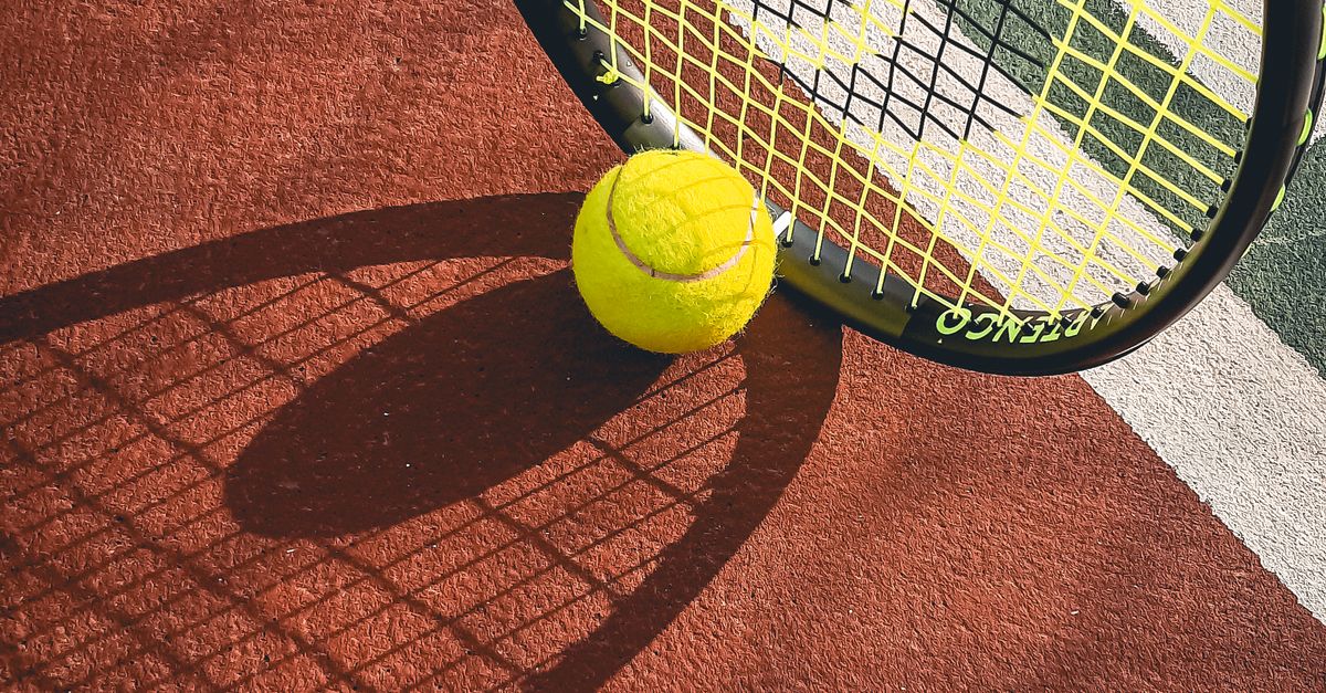 Bola tenis dan raket di atas lapangan