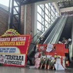 Karangan bunga protes diletakkan di depan eskalator stasiun yang tidak berfungsi