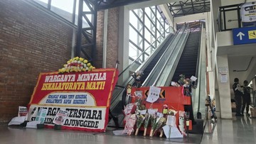 Karangan bunga protes diletakkan di depan eskalator stasiun yang tidak berfungsi