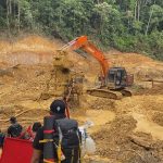 Ekskavator oranye dan para pekerja di lokasi tambang emas ilegal yang mengeruk tanah di kawasan hutan