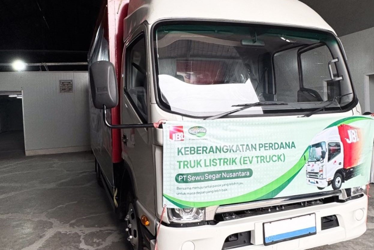 Truk listrik putih dengan spanduk keberangkatan perdana truk listrik PT Sewu Segar Nusantara, berlogo JBL dan Sunpride