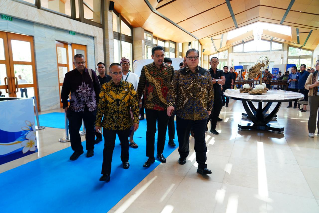 Sejumlah pejabat berbatik berjalan di atas karpet biru di aula sebuah gedung pertemuan