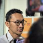 Juru Bicara KPK Budi Prasetyo berkacamata dan berbaju putih di antara kerumunan wartawan