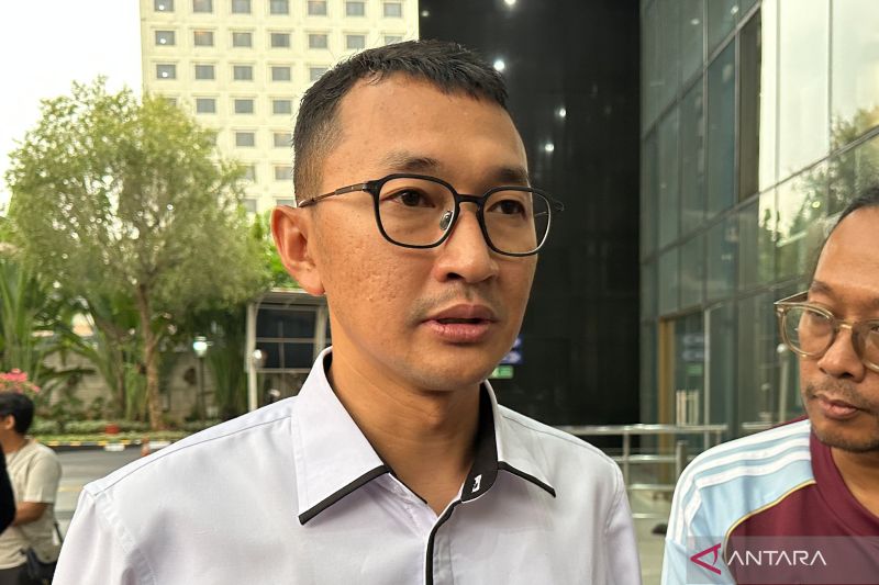 Seorang pria berkacamata berkemeja putih memberikan keterangan kepada wartawan di luar sebuah gedung bertingkat