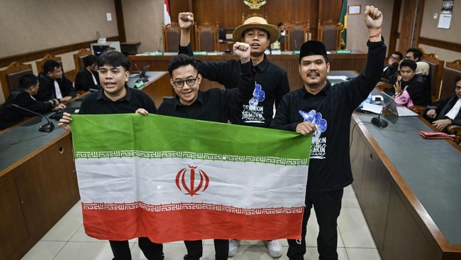 Empat terdakwa di ruang sidang pengadilan mengacungkan kepalan tangan