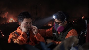 Relawan memadamkan titik api di lahan yang terbakar pada malam hari