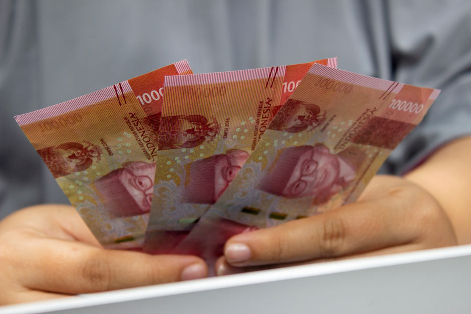 Seseorang memegang beberapa lembar uang rupiah