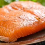 Ilustrasi potongan salmon di atas talenan dengan latar dapur