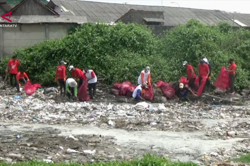 Warga dan petugas membersihkan sampah di aliran sungai