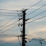 Siluet tiang dan kabel listrik dengan latar langit senja