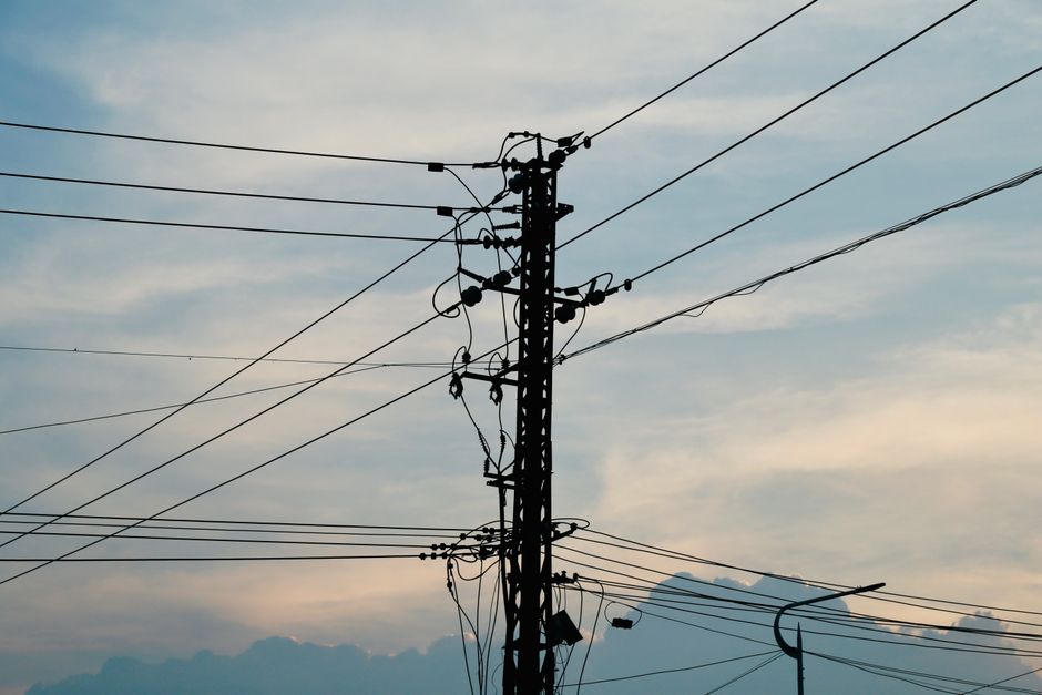 Siluet tiang dan kabel listrik dengan latar langit senja