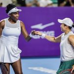 Petenis ganda putri merayakan kemenangan di lapangan tenis