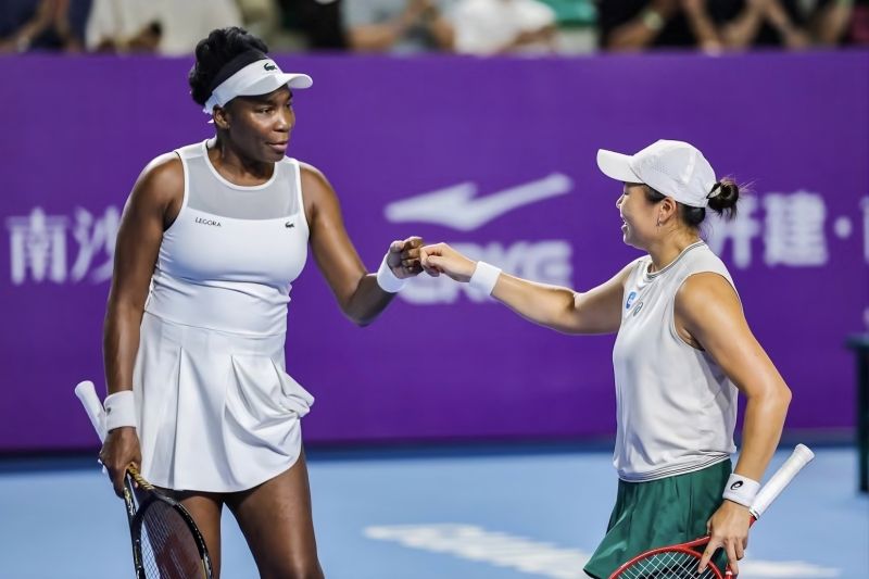 Petenis ganda putri merayakan kemenangan di lapangan tenis
