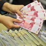 Petugas menunjukkan uang rupiah dan dolar Amerika Serikat