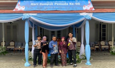 Lima anak muda berpose di bawah tenda biru dengan spanduk Upacara Peringatan Hari Sumpah Pemuda Ke-98