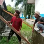 Dua warga menangani pagar sekolah yang miring di SMPN 2 Kluet Utara