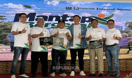 Sejumlah peserta program Mantap Bergerak berfoto bersama sambil memegang plakat di depan latar acara