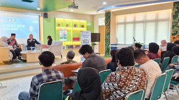 Suasana sosialisasi di sebuah ruangan, sejumlah peserta duduk menyimak pemateri di panggung