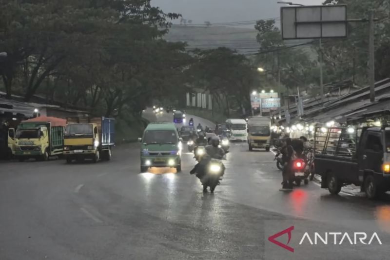 Kendaraan melintas di jalan basah saat hujan turun di kota