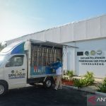 Sebuah mobil boks layanan pemenuhan gizi terparkir di depan gedung SPPG Polri Cengkareng, seorang petugas memuat barang ke bak mobil