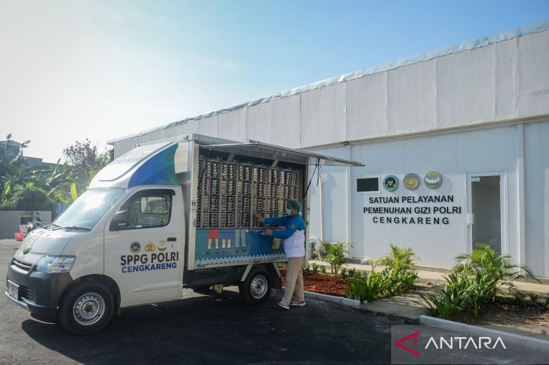 Sebuah mobil boks layanan pemenuhan gizi terparkir di depan gedung SPPG Polri Cengkareng, seorang petugas memuat barang ke bak mobil