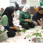 Sejumlah peserta pelatihan membuat ecoprint dengan daun-daunan di atas kain yang digelar di lantai.