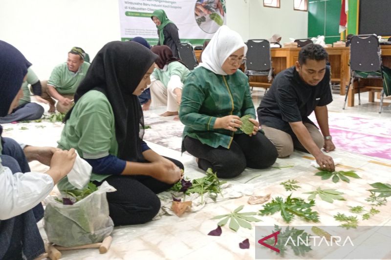 Sejumlah peserta pelatihan membuat ecoprint dengan daun-daunan di atas kain yang digelar di lantai.