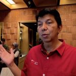 Seorang pejabat Otoritas Jasa Keuangan berbaju merah sedang berbicara dalam sebuah acara