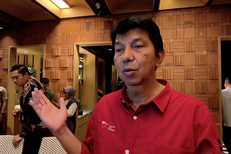 Seorang pejabat Otoritas Jasa Keuangan berbaju merah sedang berbicara dalam sebuah acara