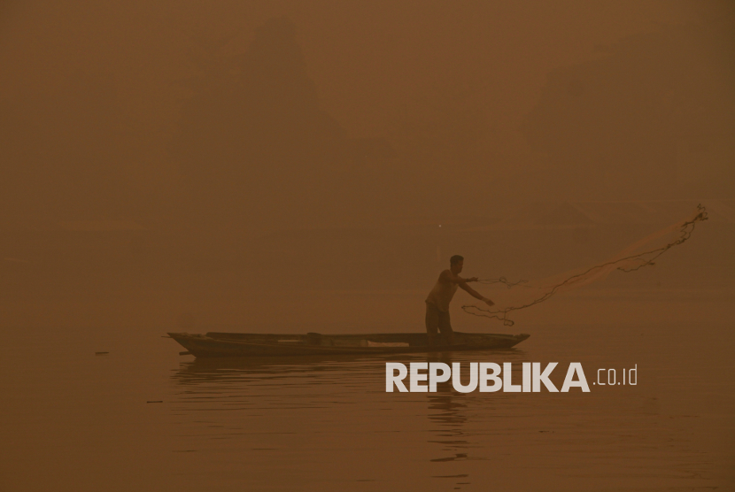 Nelayan mencari ikan di Sungai Kahayan yang diselimuti asap kebakaran hutan dan lahan