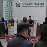 Petugas melayani peserta di kantor layanan BPJS Kesehatan dengan antrean masyarakat