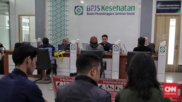 Petugas melayani peserta di kantor layanan BPJS Kesehatan dengan antrean masyarakat