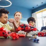 Guru dan siswa mengerjakan proyek robotik dengan model robot merah di ruang kelas