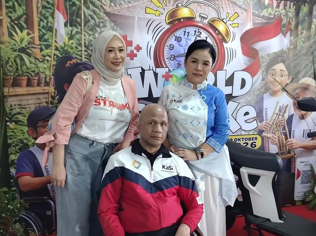 Harry Pantja berkursi roda berfoto bersama dua perempuan di depan latar acara World Stroke Day