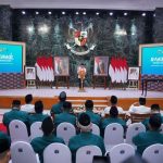 Seorang pembicara berdiri di panggung rapat kerja wilayah LDII di hadapan peserta yang duduk di aula