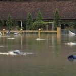 Halaman dan bangunan yang tergenang banjir dengan puing-puing mengapung di permukaan air