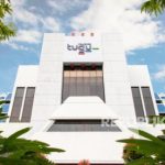 Gedung kantor Tugu Insurance dengan logo Tugu di bagian atas, dikelilingi pepohonan
