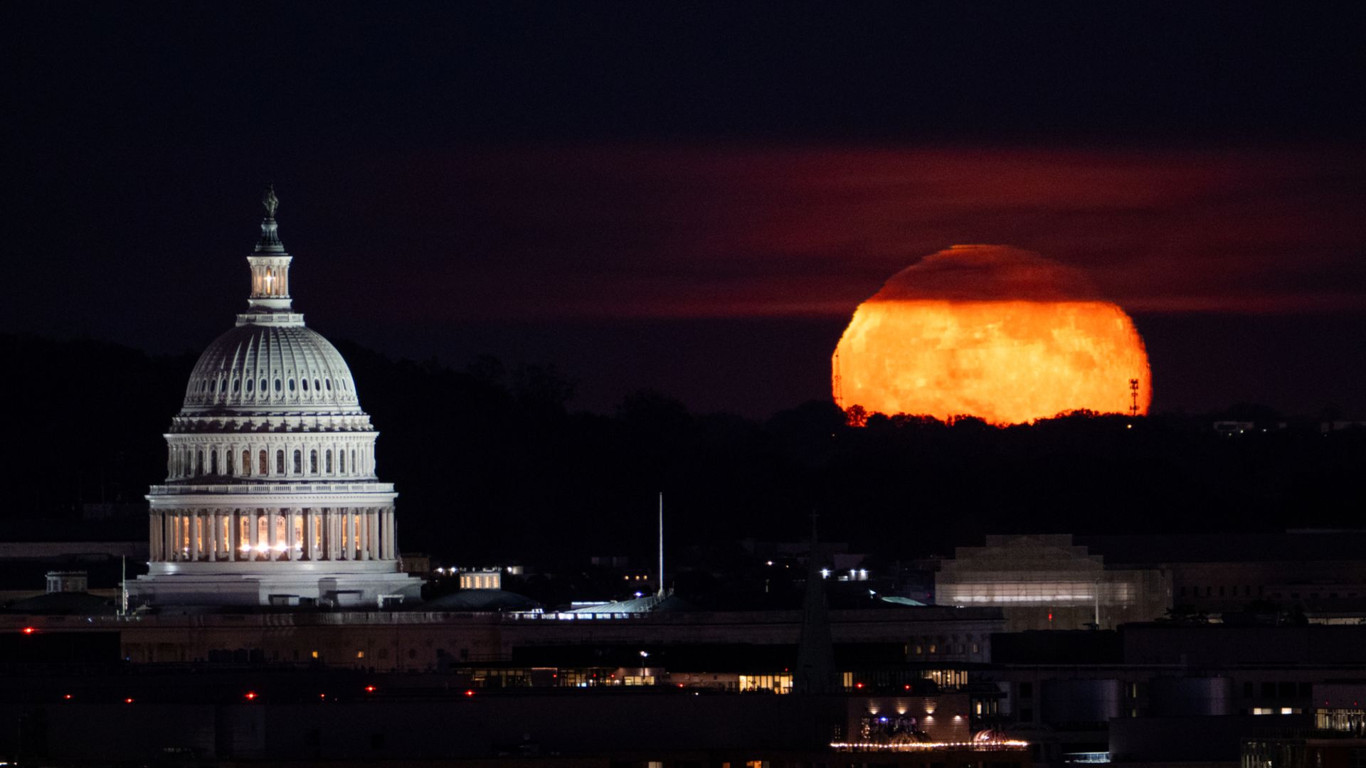 Bulan purnama besar berwarna keemasan terbit di atas cakrawala
