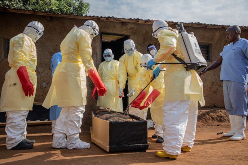 Petugas kesehatan berbusana pelindung kuning menangani jenazah di depan sebuah bangunan di wilayah wabah Ebola