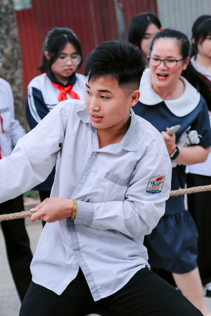 Para pelajar berseragam sekolah mengikuti lomba tarik tambang di luar ruangan dengan penuh semangat