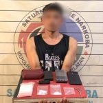 Terduga pengedar narkoba dengan wajah disamarkan menunjukkan barang bukti paket sabu, timbangan, dan telepon genggam di Mapolres Aceh Selatan