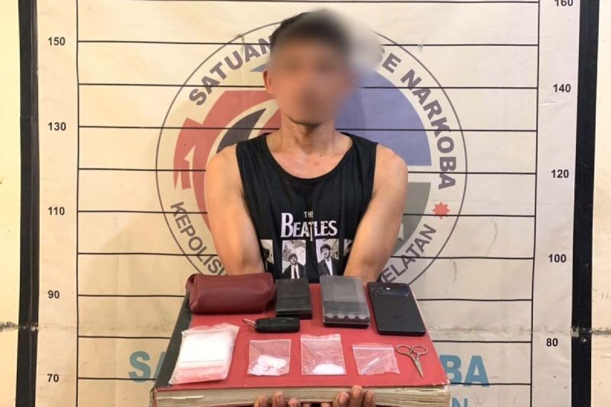 Terduga pengedar narkoba dengan wajah disamarkan menunjukkan barang bukti paket sabu, timbangan, dan telepon genggam di Mapolres Aceh Selatan