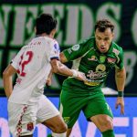 Dua pemain sepak bola berduel memperebutkan bola, satu berkostum hijau Persebaya dan satu berkostum putih Persijap