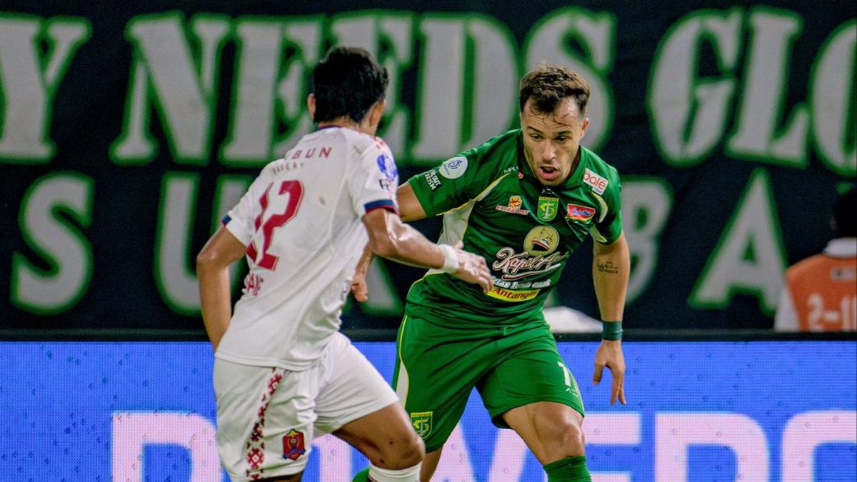 Dua pemain sepak bola berduel memperebutkan bola, satu berkostum hijau Persebaya dan satu berkostum putih Persijap
