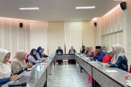 Sejumlah peserta rapat duduk mengelilingi meja berbentuk U di sebuah ruang pertemuan.