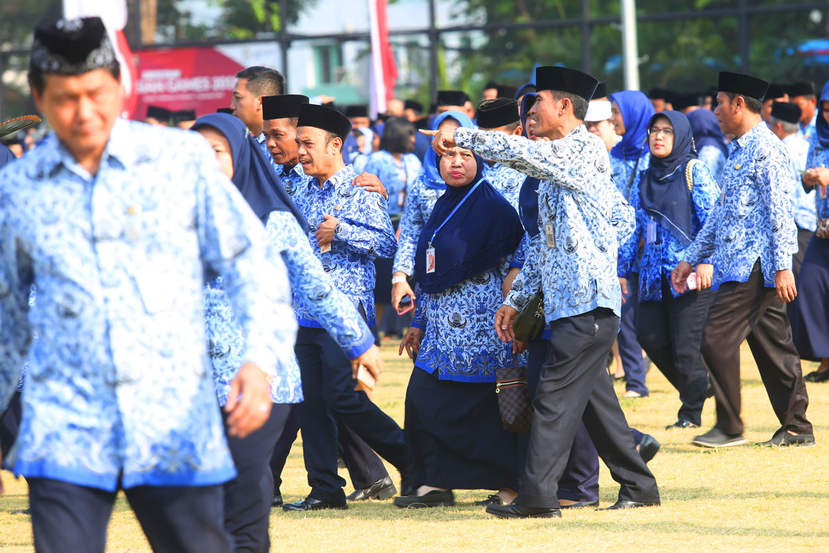 Sejumlah aparatur sipil negara berseragam batik Korpri berjalan di lapangan upacara.